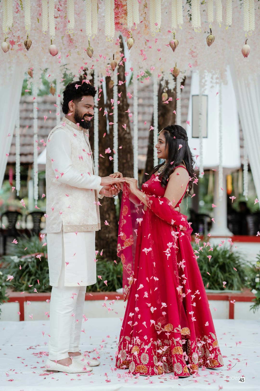 The couple under a canopy of flowers, petals falling