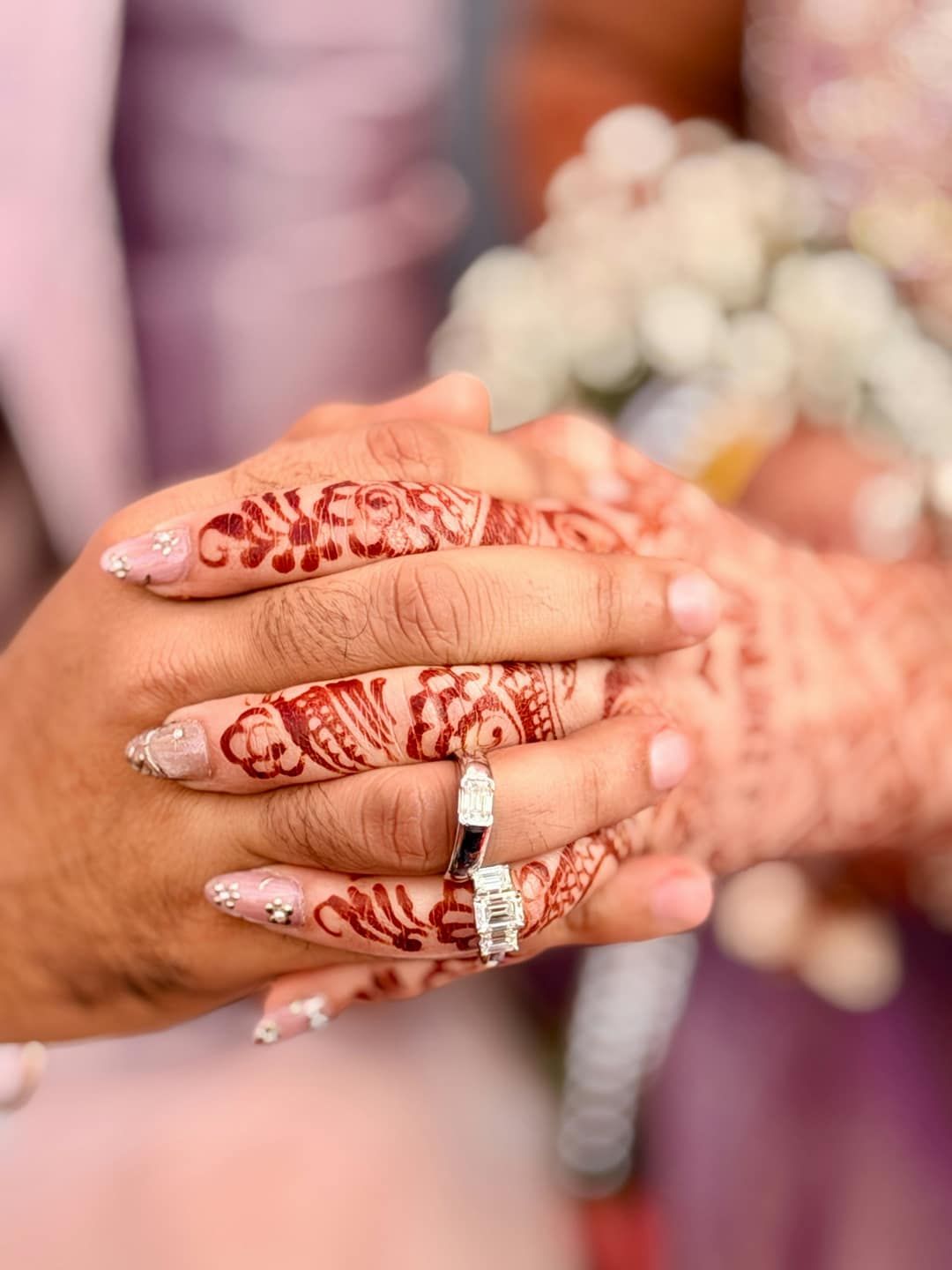The couple's hands, with henna and rings, held together