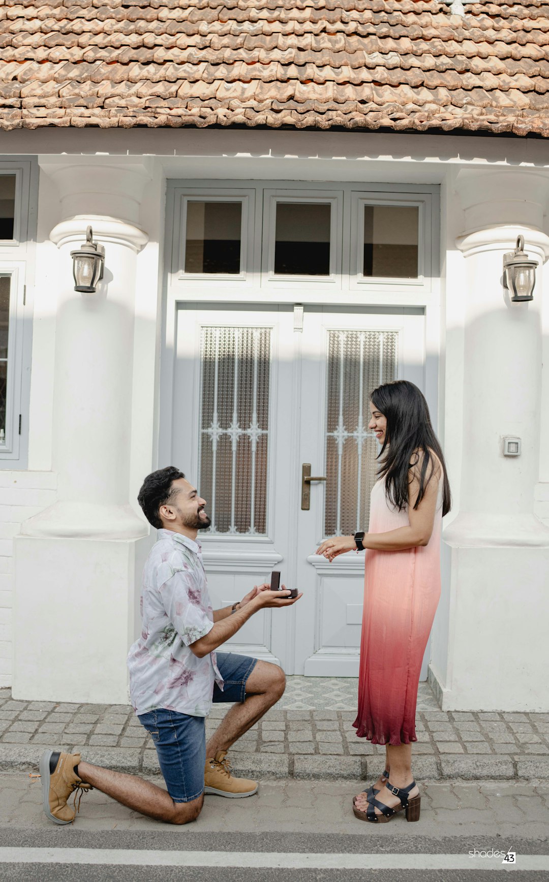 He kneels with a ring outside an old white house