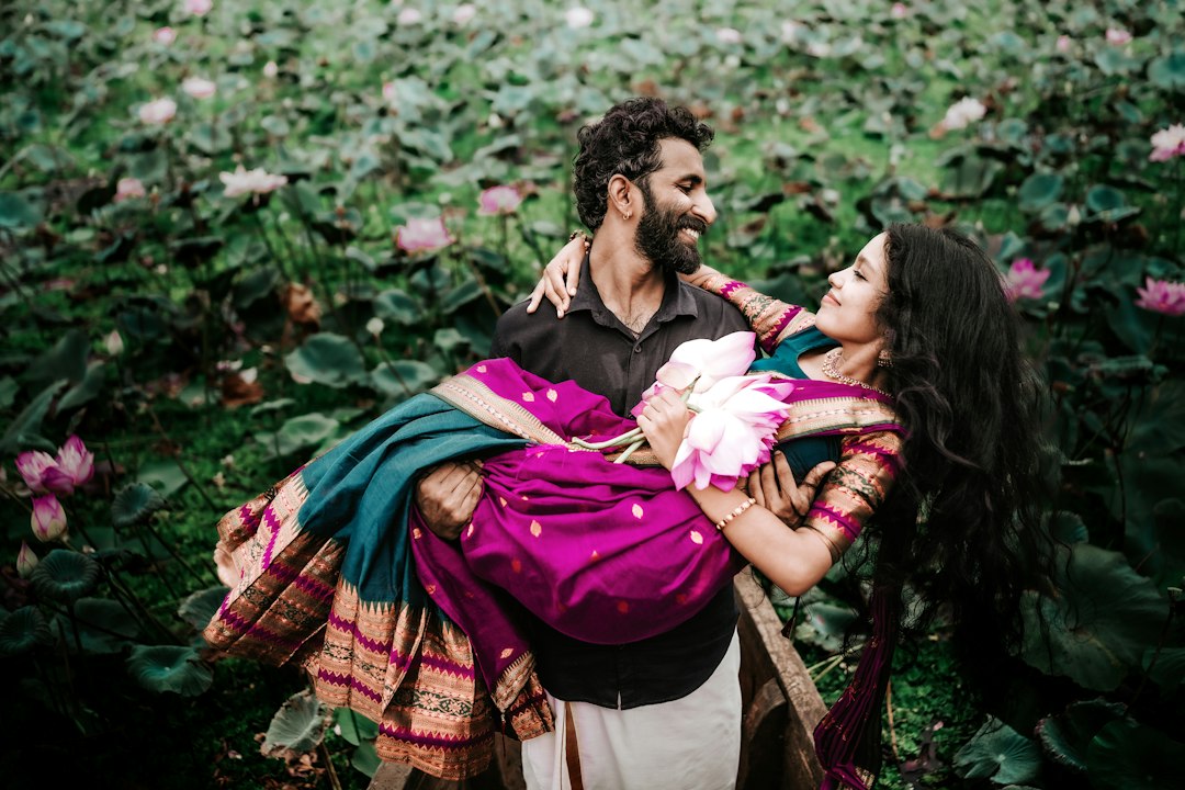 The groom carries the bride beside a lotus pond